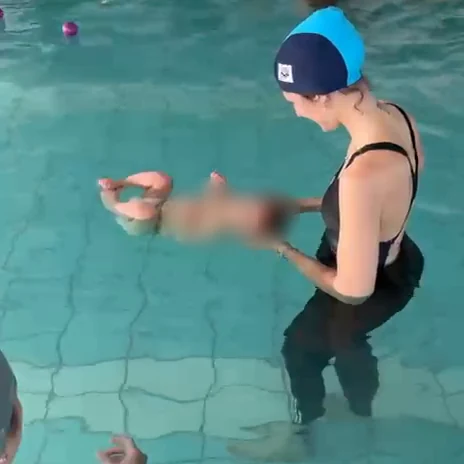 L'istruttrice sostiene un neonato che galleggia sulla schiena nell'acqua della piscina
